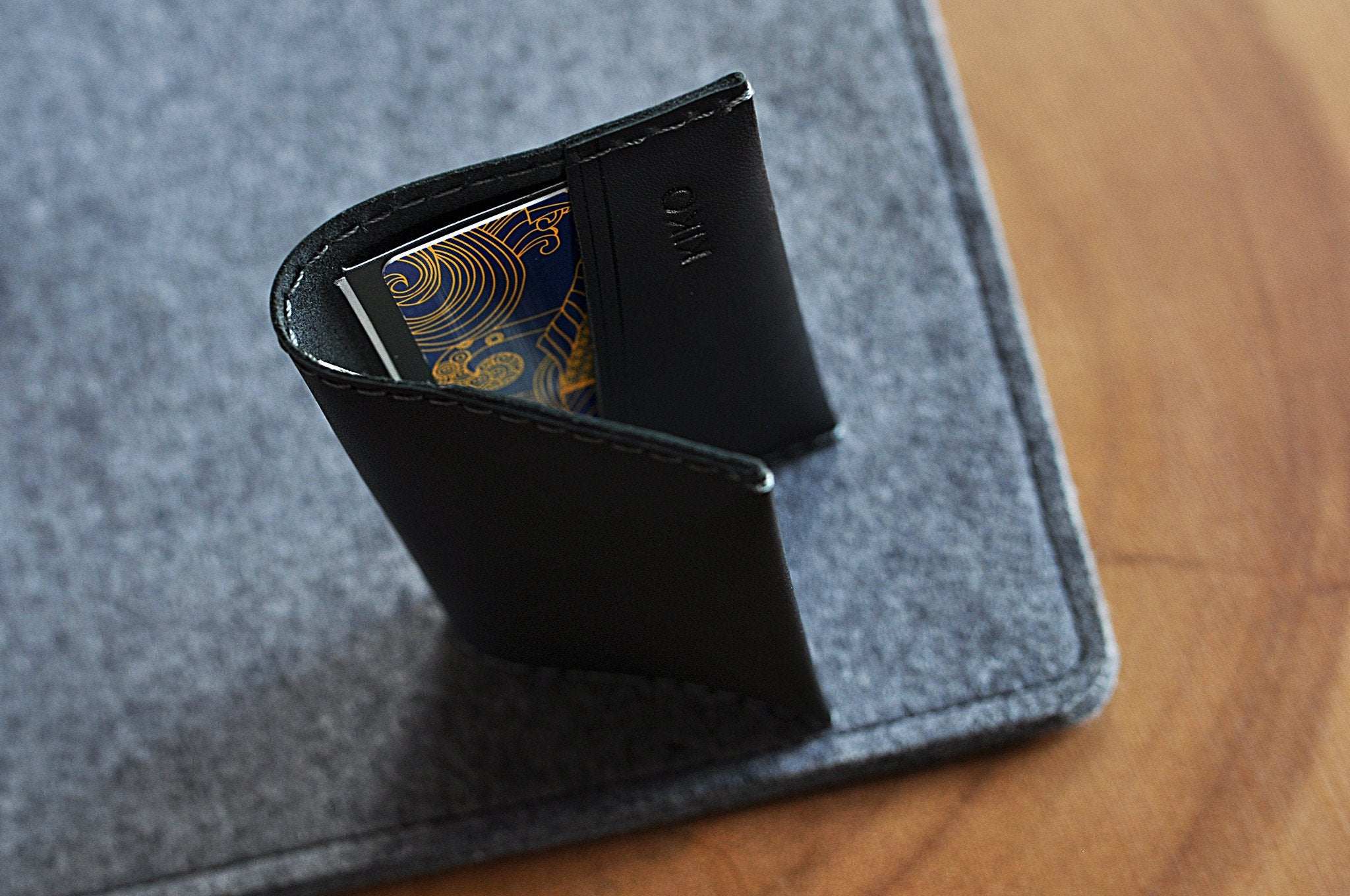 Black leather two fold card wallet with grey stitching and two card slots