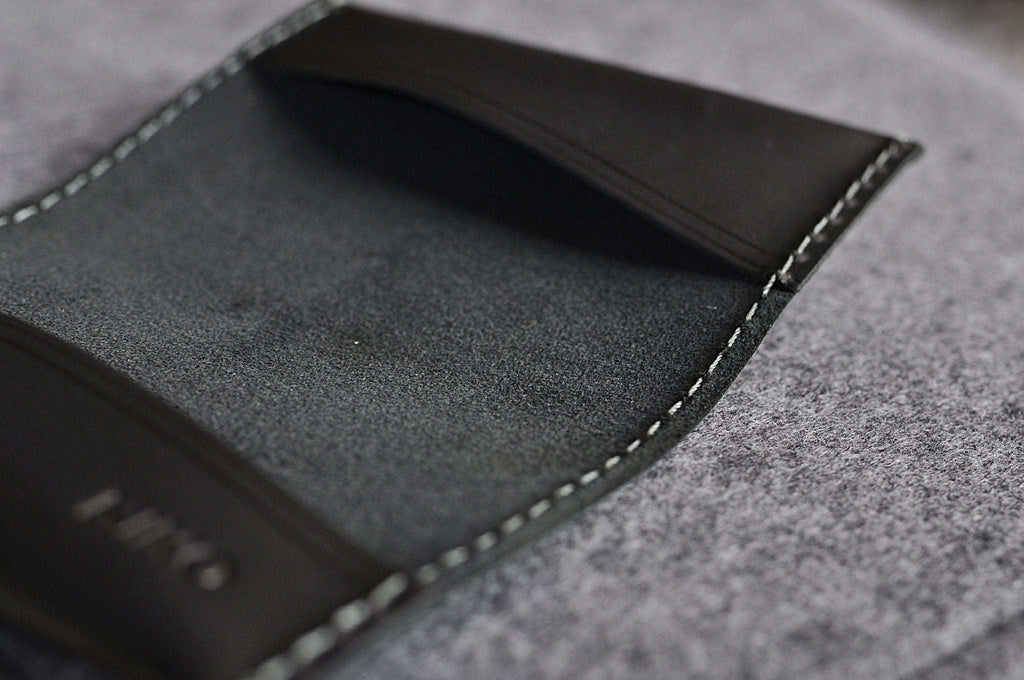Black leather two fold card wallet with grey stitching and compact design