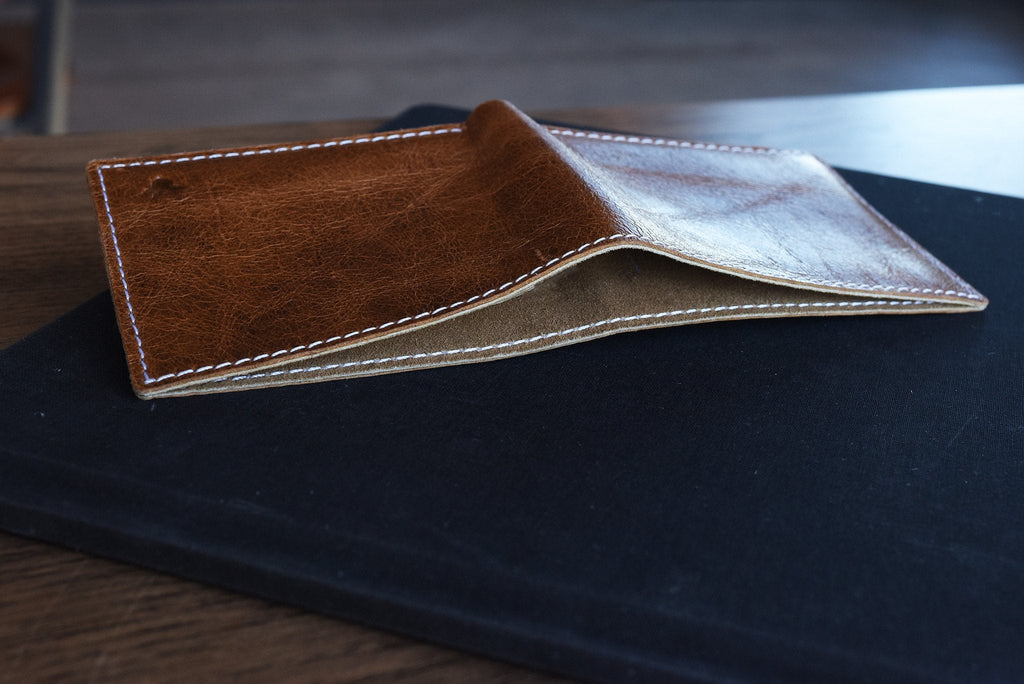 Minimalist leather bifold wallet with white stitching and hidden X detail