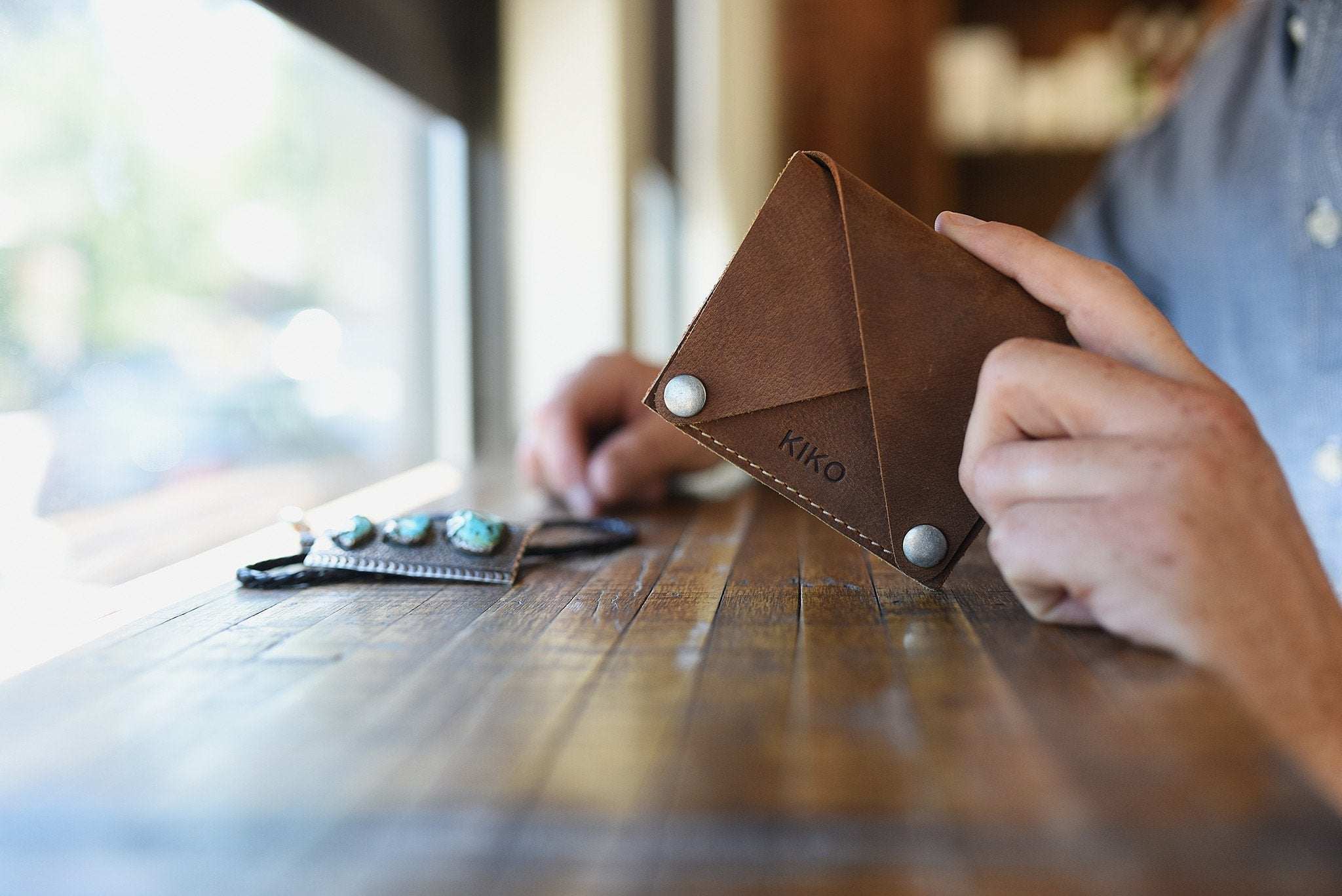 Kiko Wing Fold Wallet with geometric layered leather design, white stitching, and secure button closures
