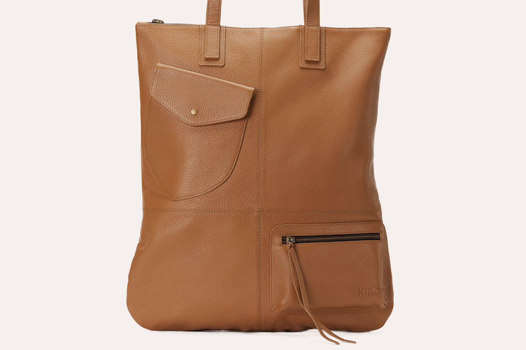 Kiko Fold n Hold Tote in cowhide leather with large interior and exterior pockets, plaid lining, and zipper tassels