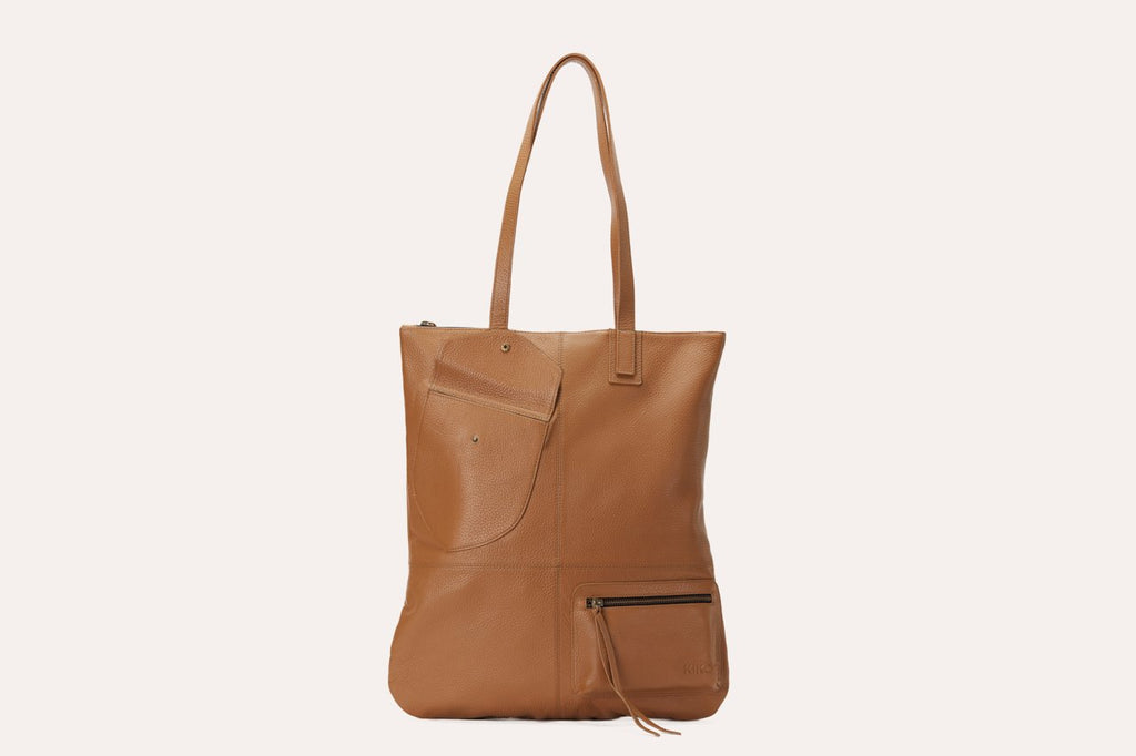 Kiko Fold n Hold Tote in cowhide leather with large interior and 2 exterior pockets, plaid lining, and zipper tassels