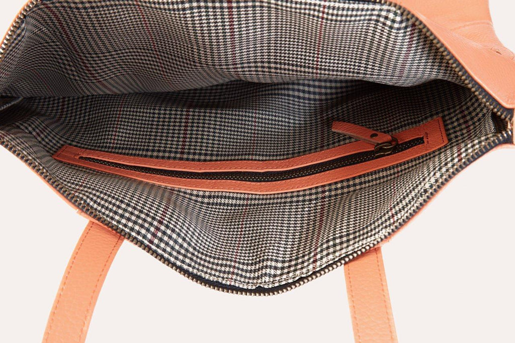 Fold n Hold Tote in cowhide leather with large interior and 2 exterior pockets, plaid lining, and zipper tassels.